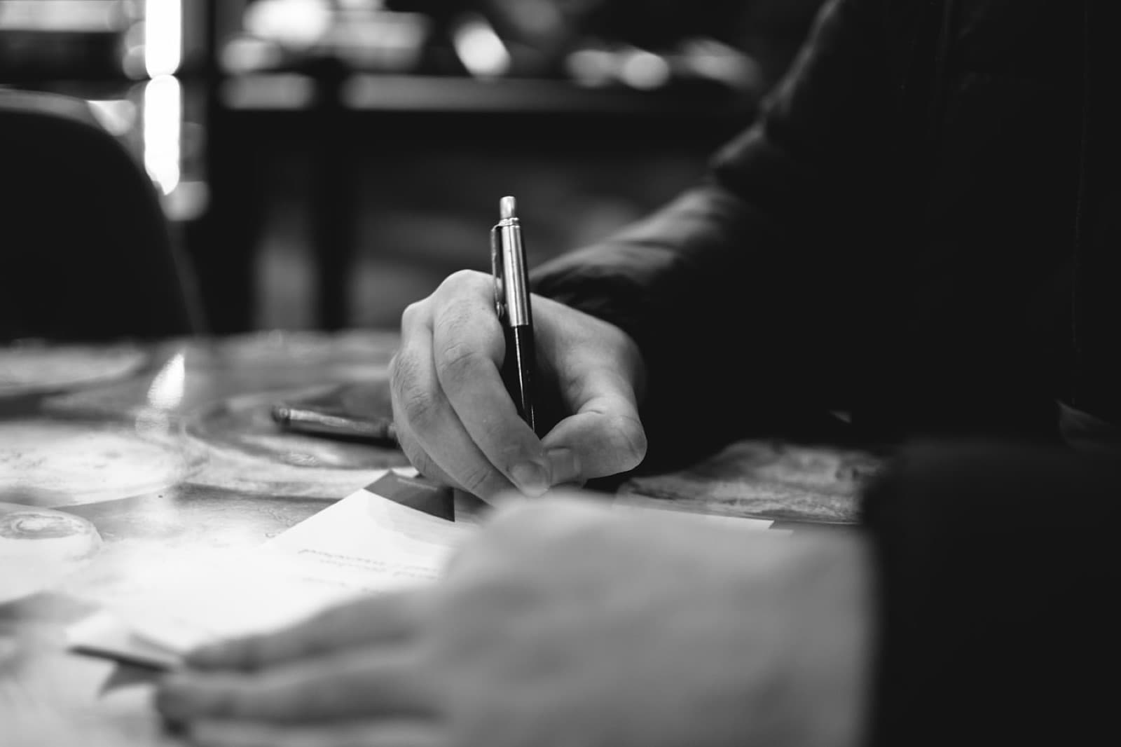 A hand writing a personalized note to a prospect with a pen