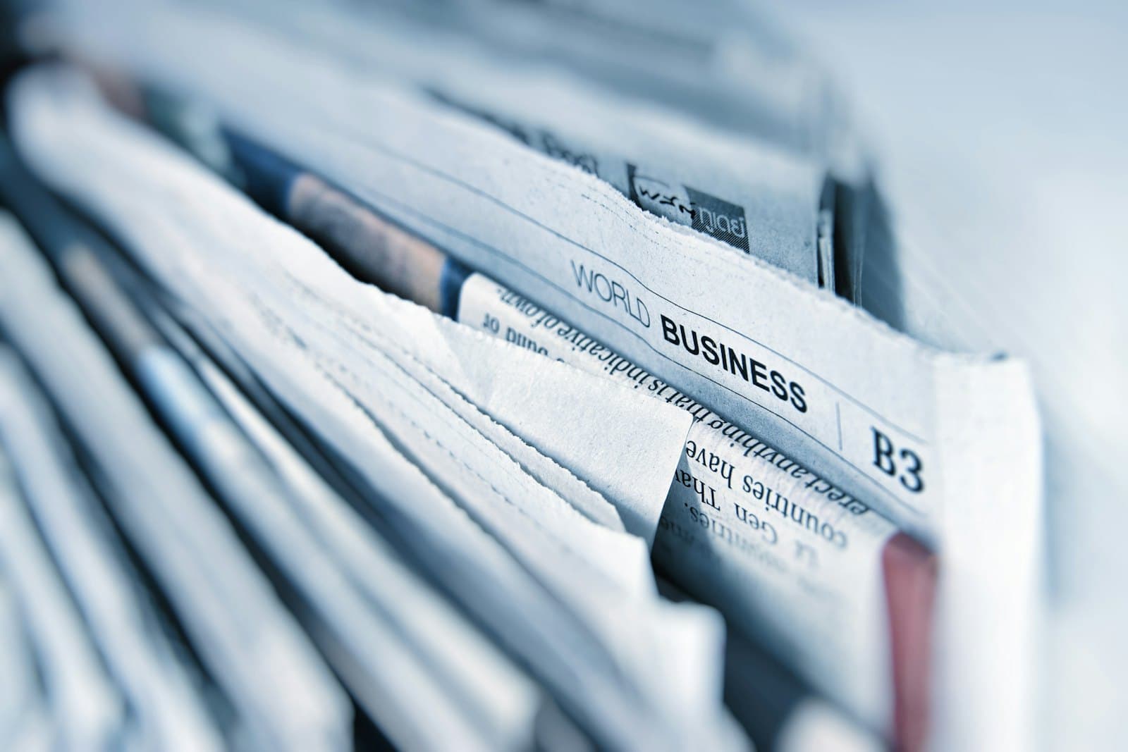 A stack of business newspapers, representing a news trigger event